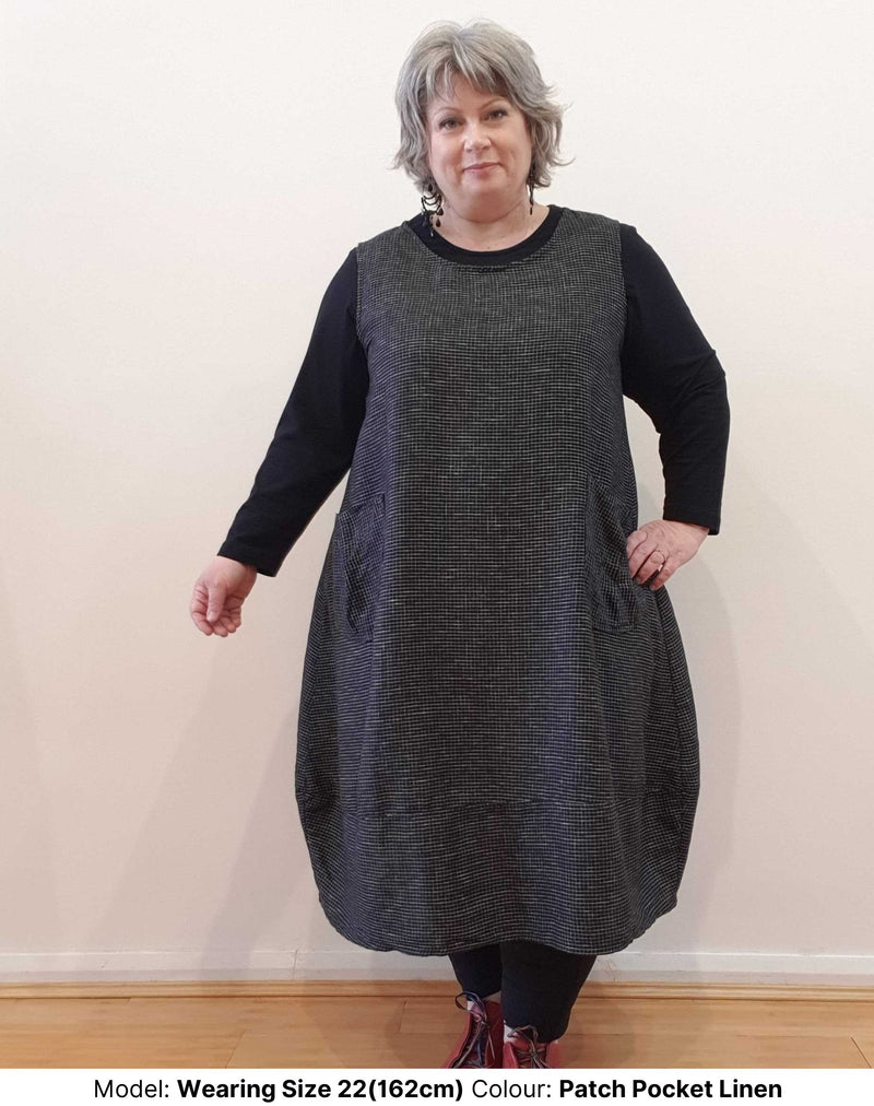 Plus size model wears Chasing Springtime plus size sleeveless dress linen tunic in black with white checks. Dress is natural fibres and made from a cotton and linen blend. Model is wearing the plus size tunic over the long sleeve plus size cotton tee shirt