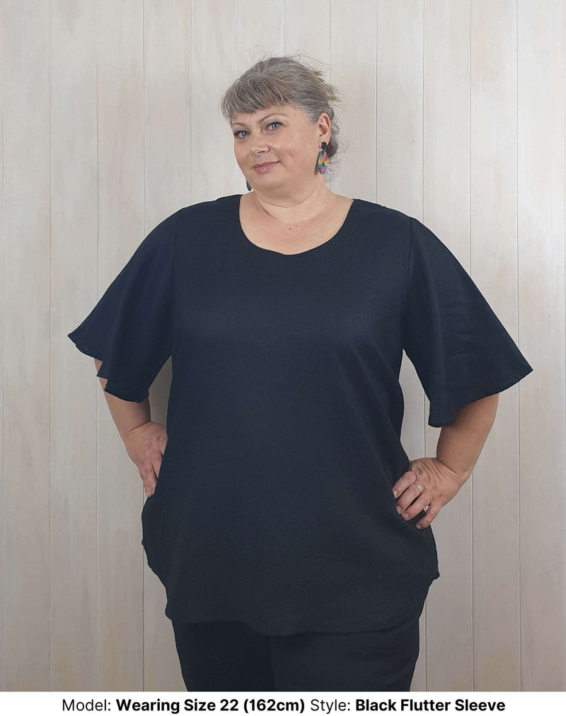 Size 22 model wearing chasing springtime plus size curvy long black linen blouse with flutter sleeves to fit larger upper arms and biceps available in sizes 14 to 26
