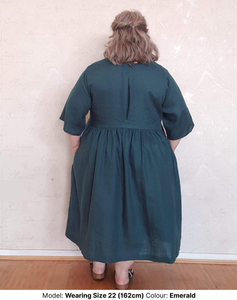 Back view of size 22 model in plus size linen dress emerald colour with pockets and round neck