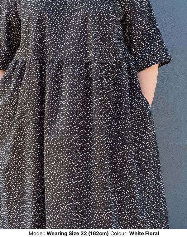 Close up of pocket and arm of model wearing size 22 plus size midi dress in black cotton with small floral motif