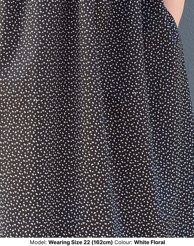 Extreme close up of detailed print on plus size midi dress in black cotton with small floral motif