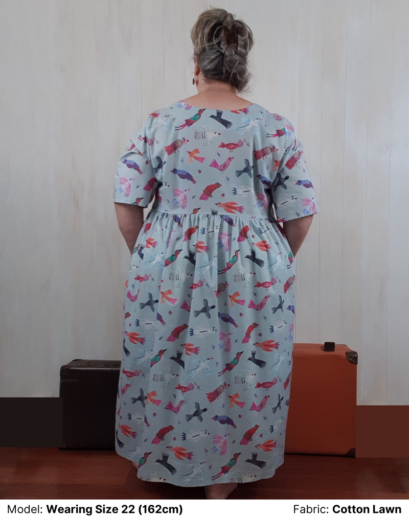 Back view of model wearing Chasing Springtime Millican Frock in pure cotton size 22. The print on the plus size dress is Gabriele Larios's print which is multi-coloured birds on a muted duck-egg blue background.