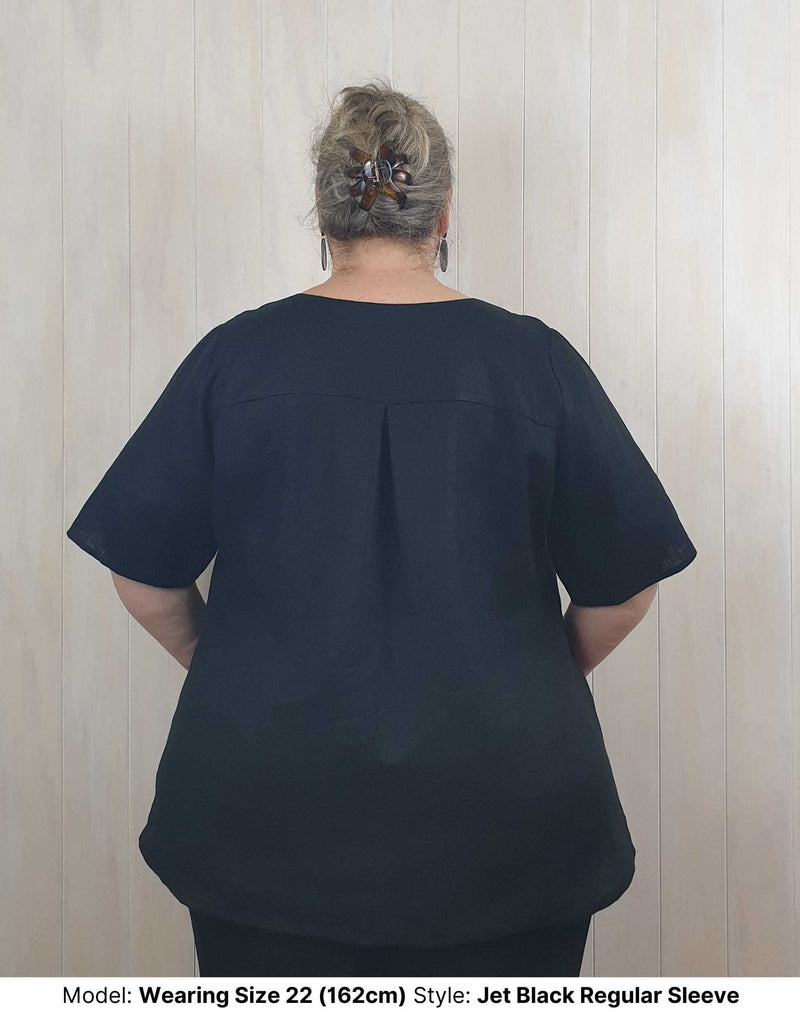 Size 22 model wears plus size curvy long jet black linen blouse with elbow length short sleeves sleeves to fit larger upper arms and biceps available in sizes 14 to 26