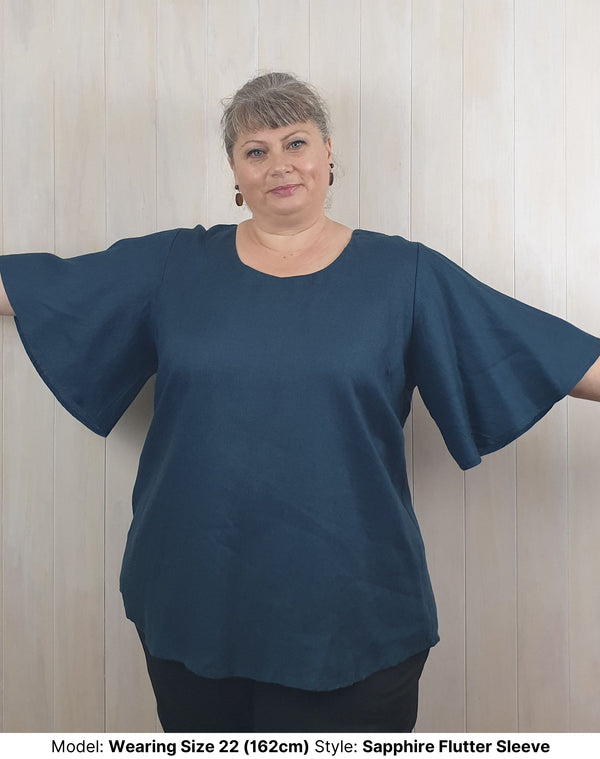 ize 22 model wearing chasing springtime plus size curvy long navy sapphire linen blouse with flutter sleeves to fit larger upper arms and biceps available in sizes 14 to 26