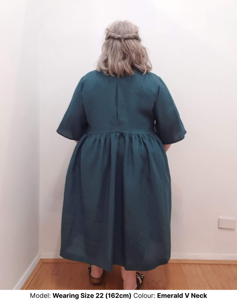 Back view of size 22 model in plus size linen dress emerald colour with pockets and v neck